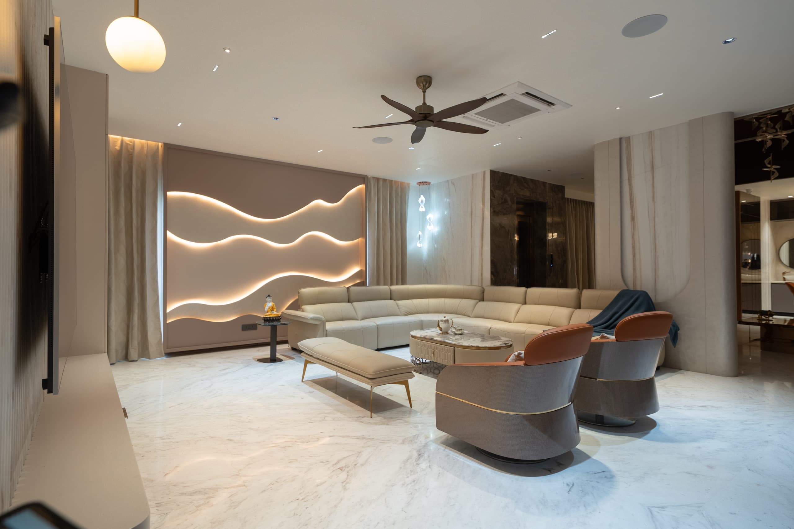 A spacious living room with a backlit wave wall and curved sectional, designed by Simplify Home