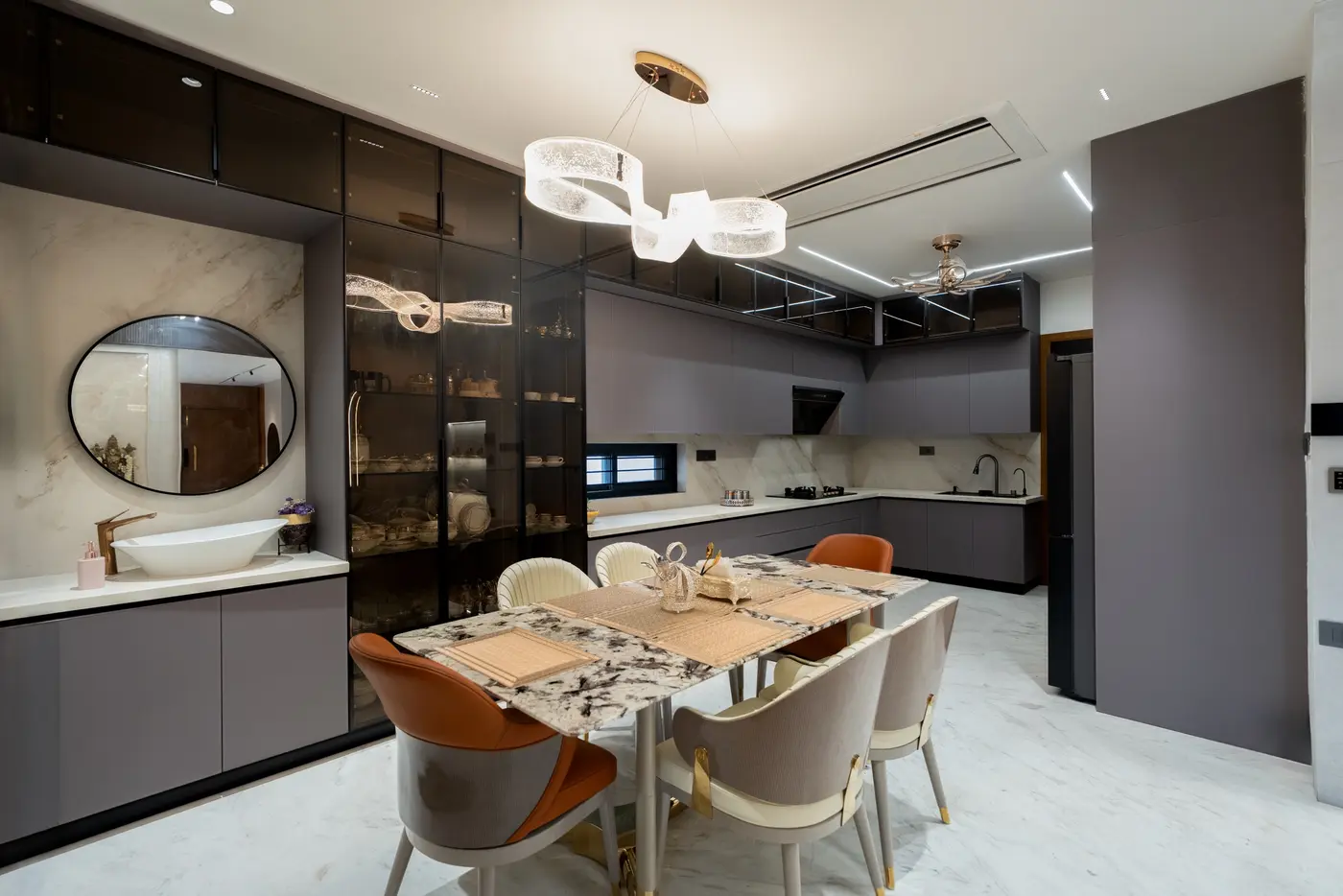 Dining area and kitchen with a stone-look counter, matte grey cabinets and brass details