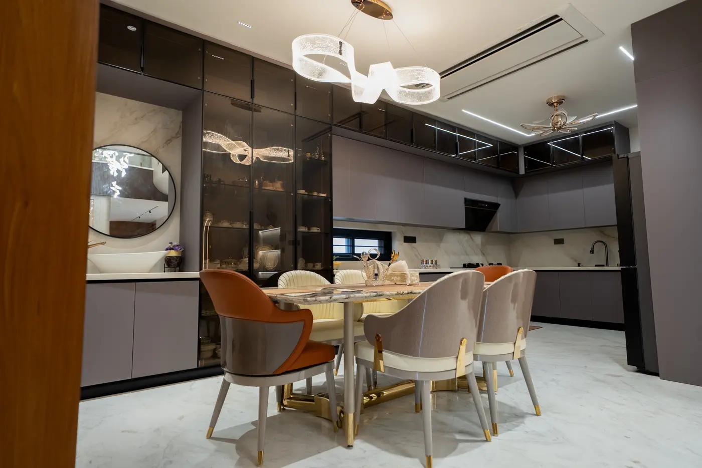 Open kitchen and dining area with glass-fronted tall units, a dining table and a sculptural pendant light