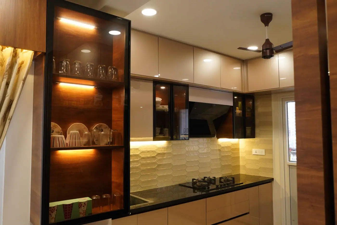 Kitchen with wood-finish tall units, lit glass display cabinets and a dark stone countertop