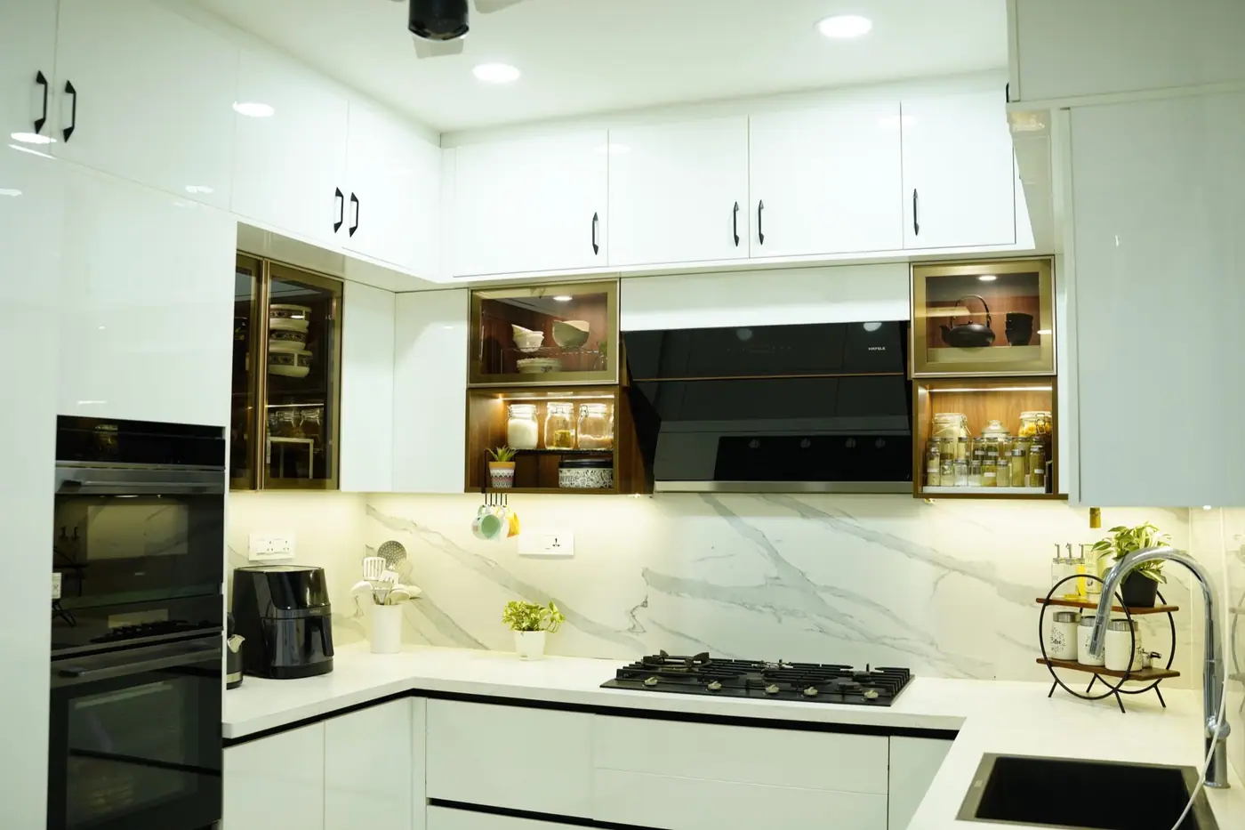 Glossy white modular kitchen with marble-look backsplash, display niches and built-in ovens