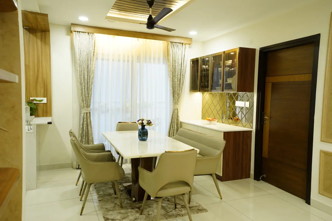 Dining area with a white marble-top table, upholstered chairs and wood-finish storage